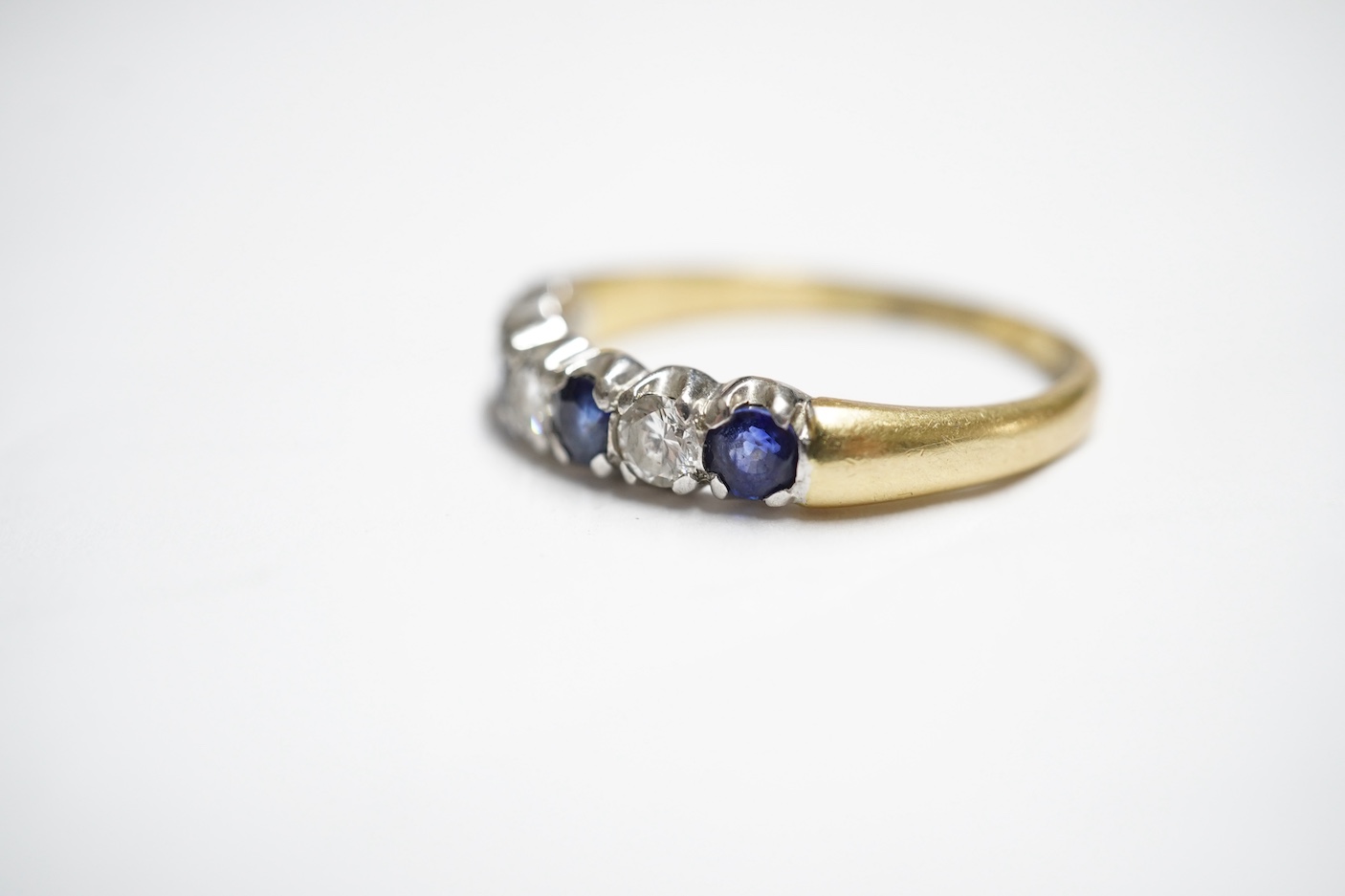 A sapphire and diamond ring, set with an alternating sequence of brilliant-cut diamonds totalling approximately 0.45 carats, and circular-cut sapphires, in 18ct gold, size Z+, British hallmarks, gross weight approximatel